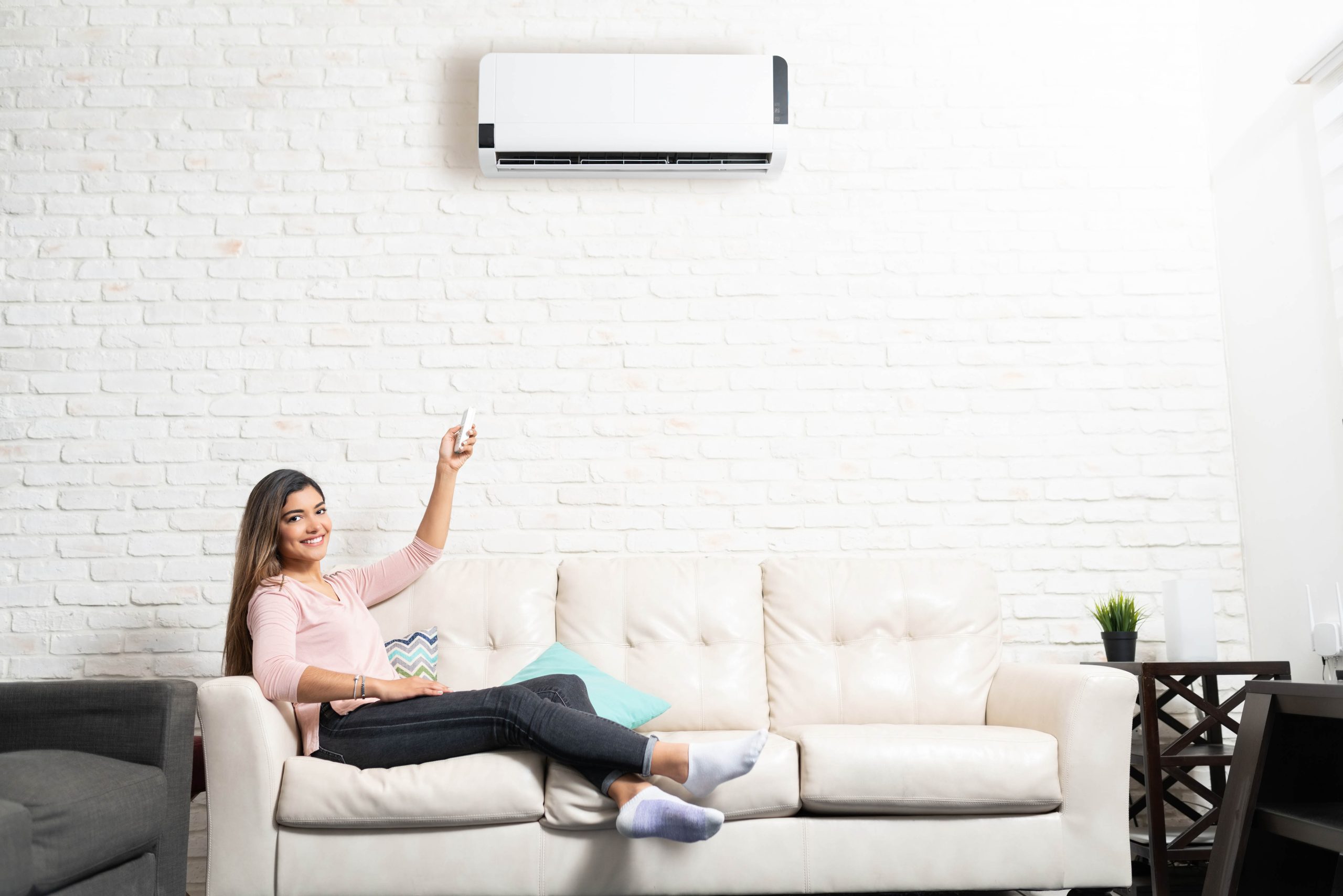 Projects smiling woman is adjusting temperature of air conditioner